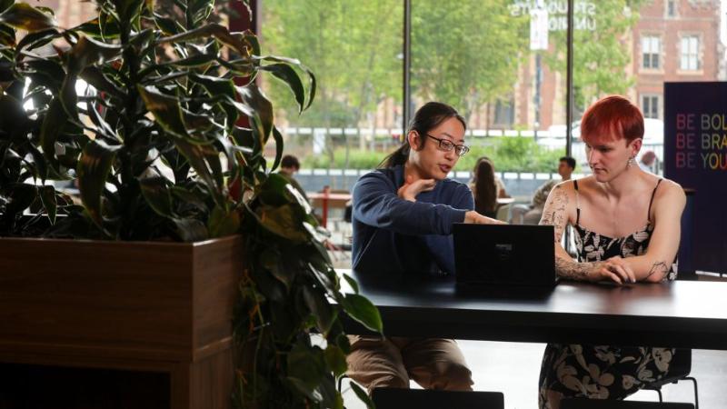 two students sitting together looking at a laptop